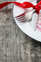 Valentine Dinner. Valentine candies with heart shape on a white plate, knife and fork on wooden table.
