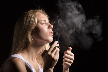 Obraz premium woman smoking joint of marijuana on black background