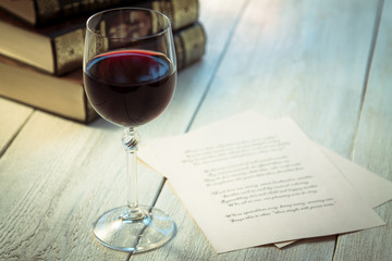 Books, a glass of wine and poetry on the old wooden table. Shakespeare Poems