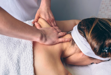 Close up of young woman receiving massage on shoulders in a clinical center. Medicine, healthcare and beauty concept. - Powered by Adobe