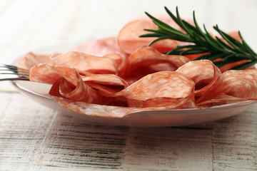 thinly sliced salami on a wooden texture on the background