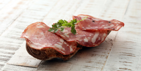 thinly sliced salami on a wooden texture on the background