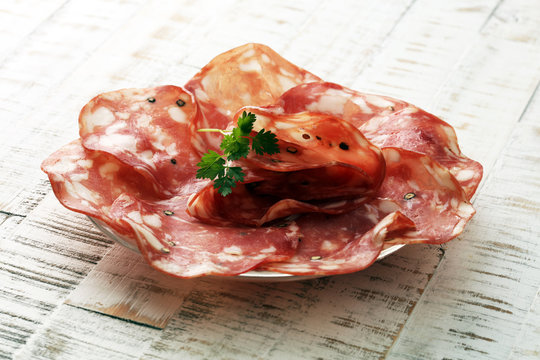 thinly sliced salami on a wooden texture on the background