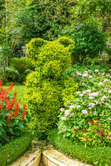 Fototapeta premium Landscape design - green figure of bear between flowers