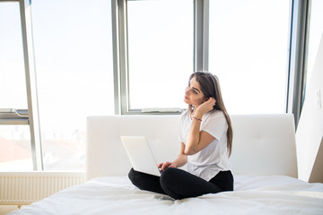 Woman in bed with laptop on legs