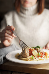 Woman eating spaghetti with meatballs