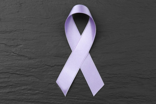 Lavender ribbon on dark textured background. Cancer and epilepsy concept