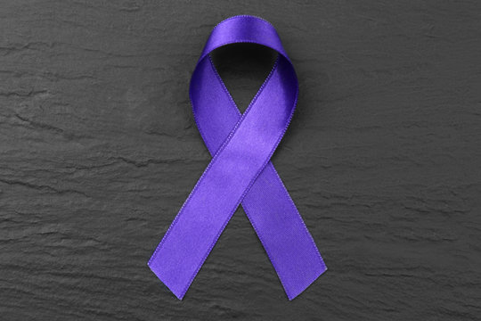 Violet ribbon on dark textured background. Family violence, Alzheimer disease and pancreas cancer concept
