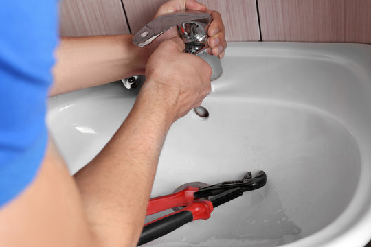Closeup of plumber fixing tap on sink