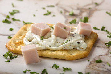 Thin crispy crackers with cream cheese, ham and herbs