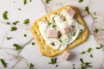 Thin crispy crackers with cream cheese, ham and herbs