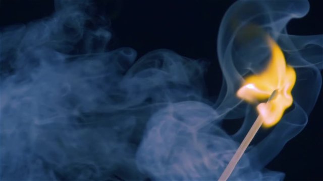 Burning match on a black background in slow motion