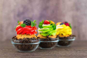 Colorful cupcakes with berries of coffee beans on a wooden background. Focus on the foreground.
