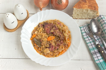 Sauerkraut with smoked pork meat in plate on white table