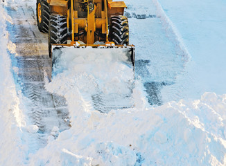 Snow drifts. Tractor clears the way after heavy snowfall.