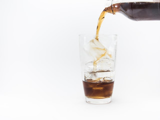 cola pouring from a plastic bottle into a glass filled with ice cubes