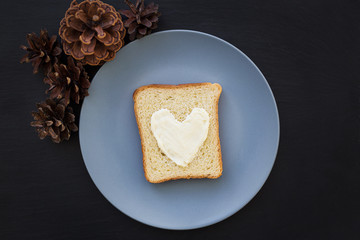 sandwich for breakfast in the form of heart with cheese on a blue plate and black background with cones