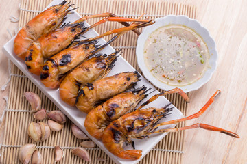 Burn shrim and Seafood sauce on wooden table.