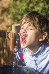 Little boy drinking water from a fountain