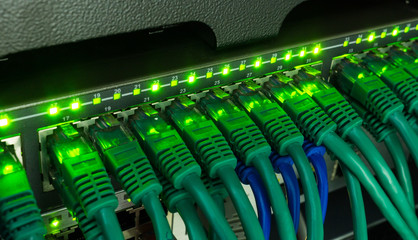 Network switch and ethernet cables glowing in server room