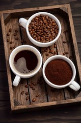 Different types of coffee - ground, grain and beverage on dark wooden background, selective focus, vertical.