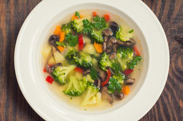 Vegetable soup with broccoli, mushrooms and herbs. Wooden background. Top view. Close-up