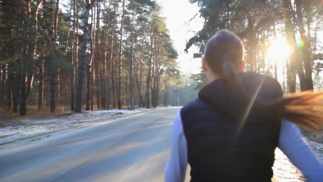 Young woman with a slender figure is engaged in gymnastics at sunrise. She makes a run along the forest. Camera stabilizer steadycam shot.