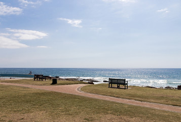 Two Benches on Grass Verge Against Ocean Skyline