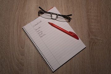 Einkaufsliste auf  einem Tisch mit Brille und Kugelschreiber