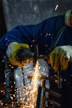 Man Sawing Metal With A Rotary Angle Grinder On Work Table And Generating Sparks