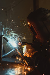 Welding metal with a flash of hot sparks on a work table, in an industrial workshop