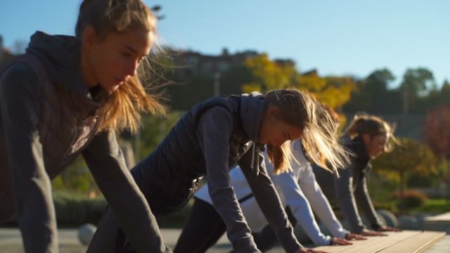 Young healthy friends doing push ups in the beautiful park slow motion