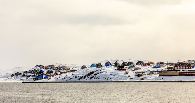 Colorful cabins on the hill covered in snow, Aasiaat city panora