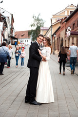 Fototapeta premium gorgeous happy wedding couple walking and kissing in the old city of Minsk, Belarus