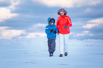 Fototapeta na wymiar Cute little boy and his mother on icy beach