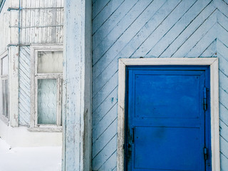 Wooden aged blue and white house facade with navy blue door and window