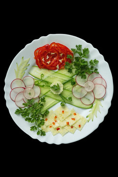 Beautifully sliced vegetables on a white plate. White plate with vegetables isolated on a black background. Apitizer.