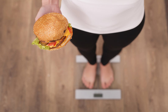 Diet And Fast Food Concept. Overweight Woman Standing On Weighin