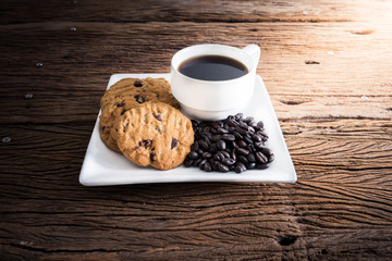 Coffee cup with chocolate cookie on dark wooden