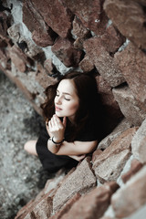 beautiful sad young woman on a stone wall background