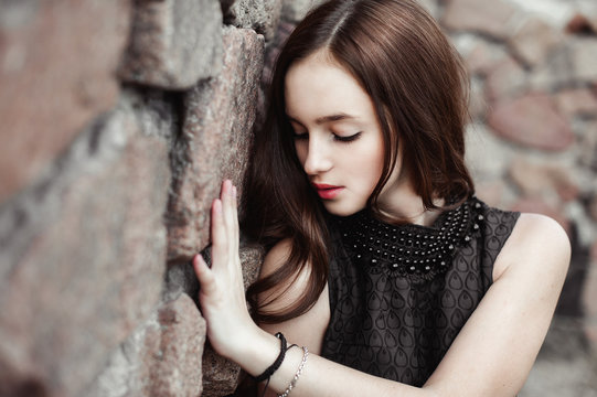 beautiful sad young woman on a stone wall background