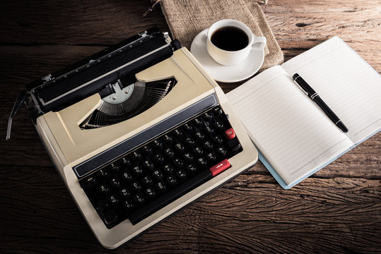 Vintage typewriter and a blank notebook , pen and coffee cup