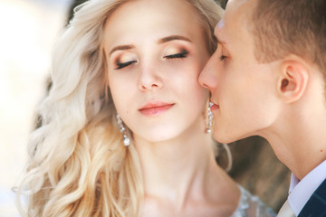 Fototapeta premium Wedding .Bride and Groom, Kissing at a Beautiful park on the wedding day., Romantic Married Couple .Wedding couple outdoors is hugging each other. Beautiful model girl in white dress. Man in suit. 