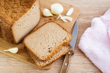 Куски ржаного домашнего хлеба, лук, чеснок, нож и салфетка