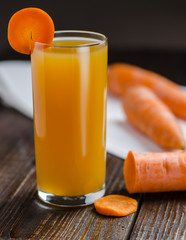 Carrot juice and carrots on wooden table.