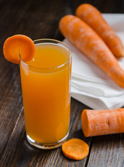 Carrot juice and fresh carrots on wooden table