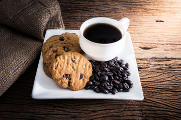 Coffee cup with chocolate cookie on dark wooden