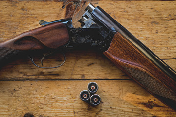 Shotgun charged with bullets and spare bullets on wooden floor,