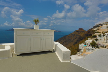 Santorini Island Greece - olive tree in a pot on white chest of drawers, overlooking the blue sea