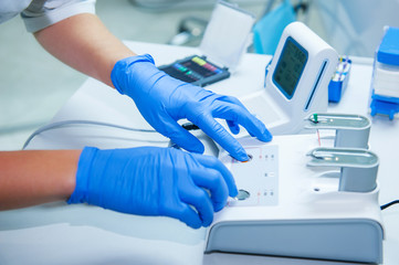 Assistant's hands configures dental equipment in dentist's office. Close up, selective focus. Dentistry